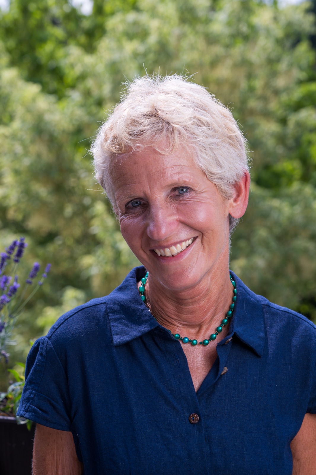 Susanne Benda lächelnd im Garten, in dunkelblauer Bluse